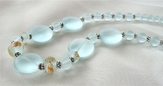 Polished Sea Glass, Artisan Lampwork beads with touches of sand in light azure. Finished at 19 inches with a hummingbird pewter toggle clasp.